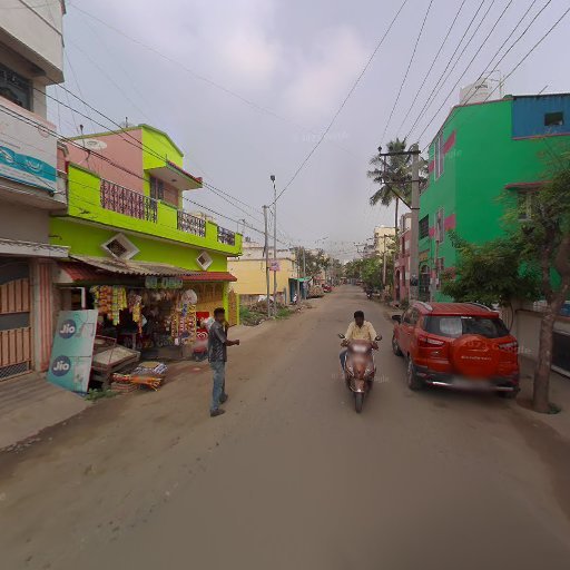 Street scene with colorful buildings, a small shop, a red car parked, and a person riding a scooter on the road.
