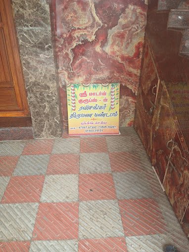 Colorful sign with Tamil text against a marble wall, set on a red and gray checkered floor.